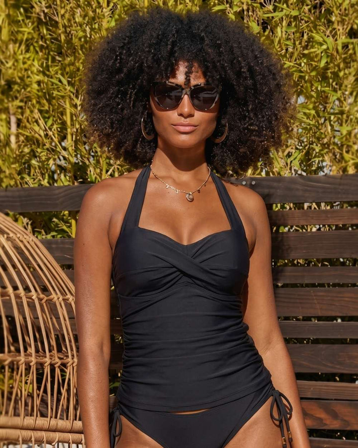 Woman wearing a black swimsuit with sunglasses against a natural background
